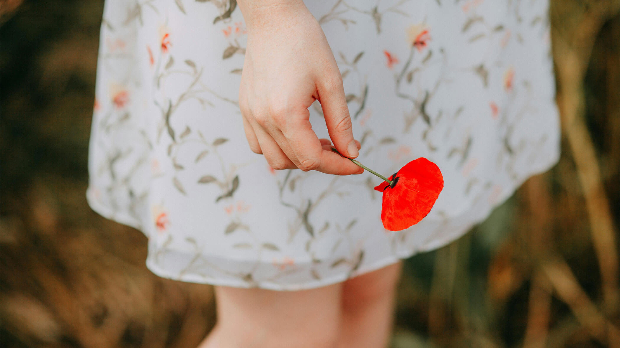 Frau hält eine Mohnblume in der Hand - Der Forsterhof